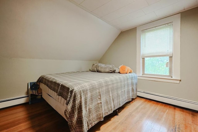 bedroom featuring vaulted ceiling, wood-type flooring, and baseboard heating