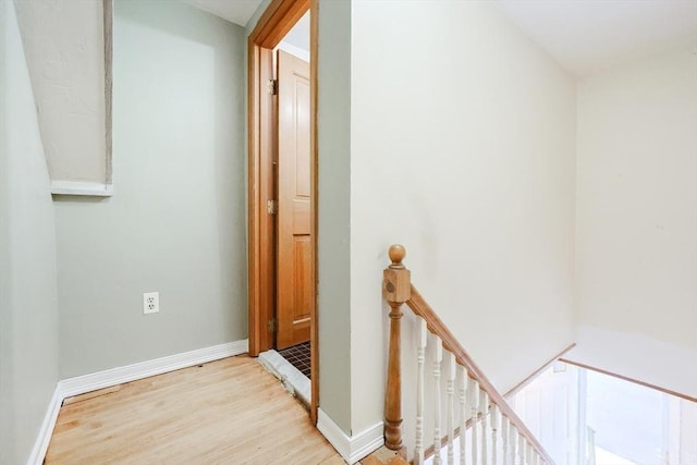 hallway with an upstairs landing, wood finished floors, and baseboards