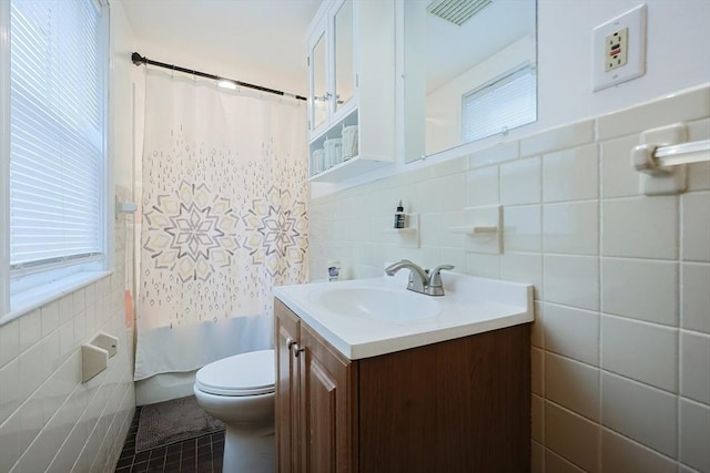 full bath featuring tile walls, toilet, vanity, plenty of natural light, and tile patterned floors