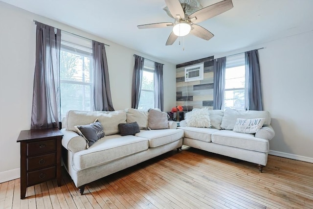 living room with light wood-type flooring, baseboards, and ceiling fan