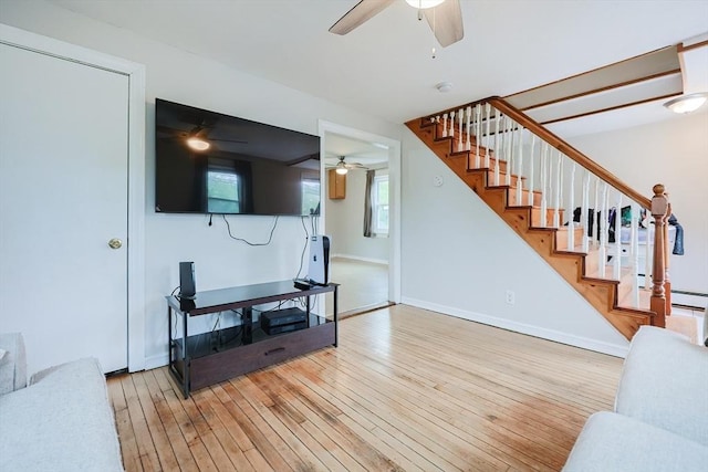 living room featuring ceiling fan, wood-type flooring, stairs, and baseboards