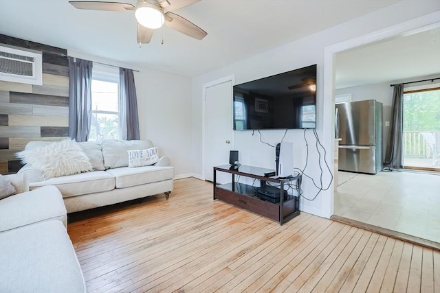 living room featuring wood-type flooring, ceiling fan, and a wall unit AC