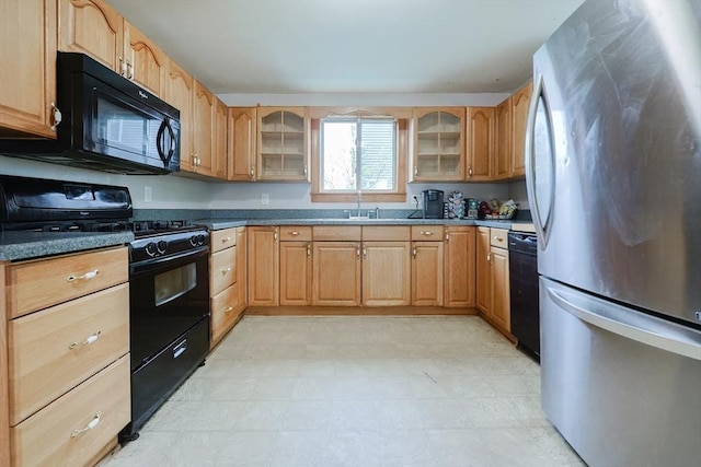 kitchen featuring black appliances, a sink, glass insert cabinets, and light floors
