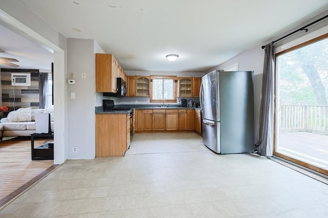 kitchen with freestanding refrigerator, gas range oven, black microwave, glass insert cabinets, and dark countertops