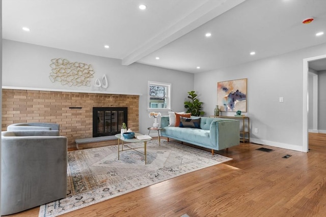 living room featuring hardwood / wood-style flooring, a fireplace, and beam ceiling