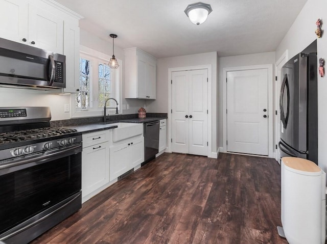 kitchen featuring dark countertops, dark wood finished floors, a sink, white cabinets, and stainless steel appliances