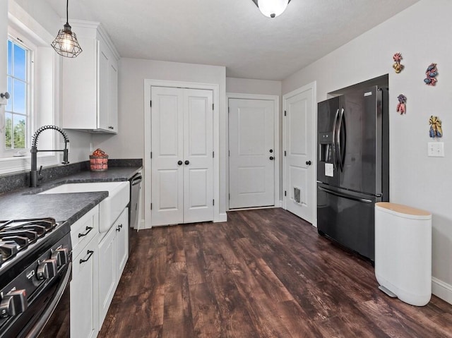 kitchen featuring dark countertops, dark wood-type flooring, white cabinetry, a sink, and black appliances