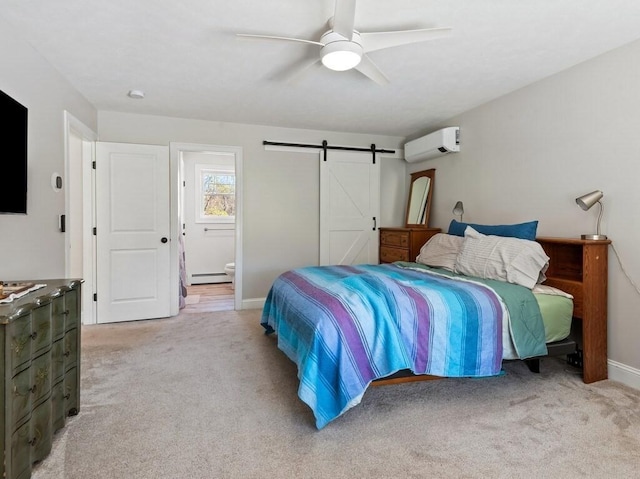 bedroom featuring a wall mounted AC, a barn door, baseboards, connected bathroom, and light carpet