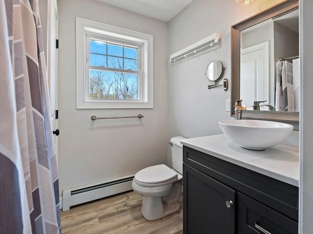 bathroom with vanity, toilet, wood finished floors, and a baseboard radiator