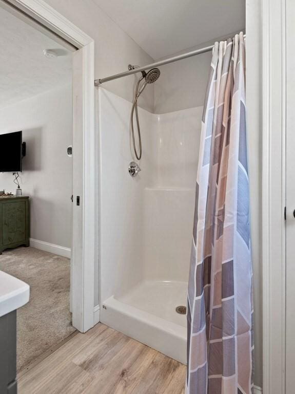 bathroom with vanity, baseboards, a stall shower, and wood finished floors