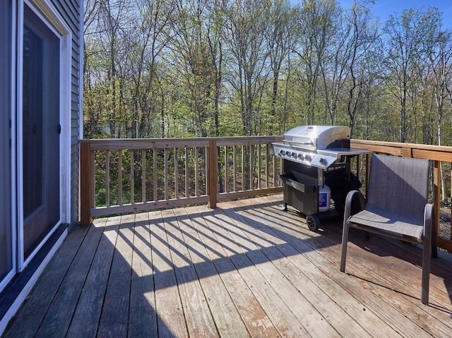 deck with grilling area and a view of trees