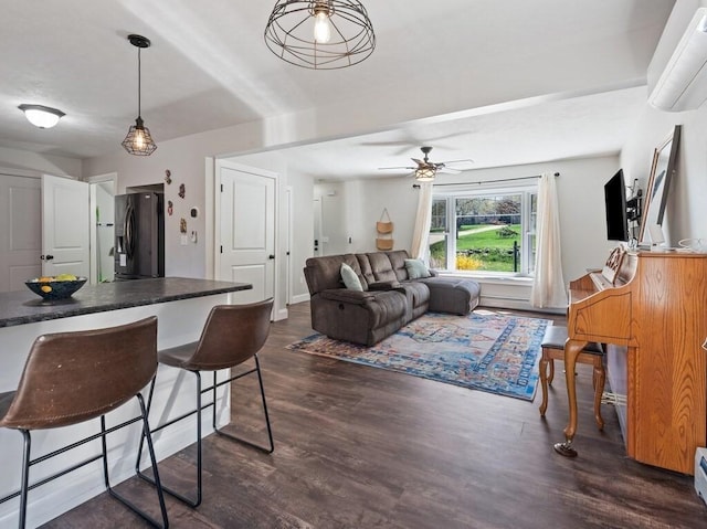 living area with dark wood-type flooring, a wall mounted air conditioner, a ceiling fan, and a baseboard heating unit