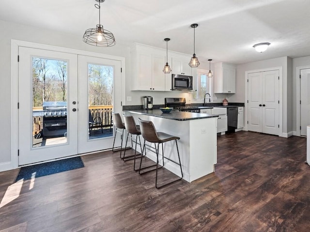 kitchen with a healthy amount of sunlight, dark countertops, stainless steel appliances, and a peninsula
