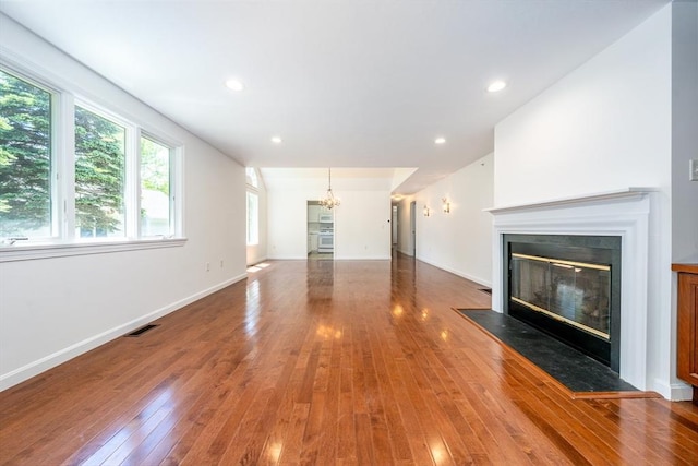 9 Longwood Rd Unit 239, Mashpee, MA 02649 - unfurnished living room featuring wood-type flooring, a chandelier, a glass covered fireplace, baseboards, and recessed lighting