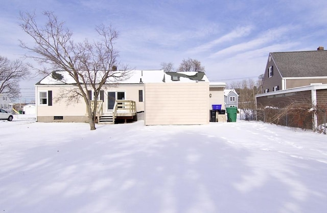 snow covered back of property featuring a deck