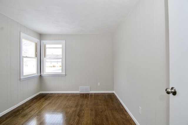 spare room featuring dark wood-type flooring and wooden walls