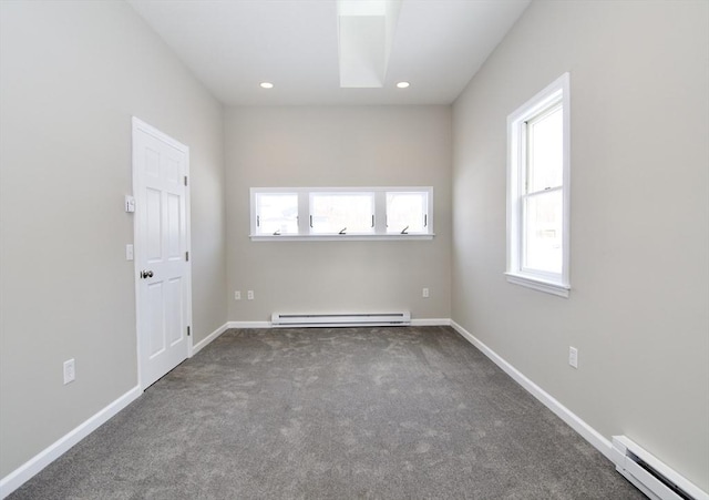 unfurnished room featuring a baseboard heating unit and dark carpet