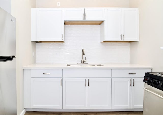 kitchen with sink, white cabinetry, fridge, stainless steel stove, and decorative backsplash