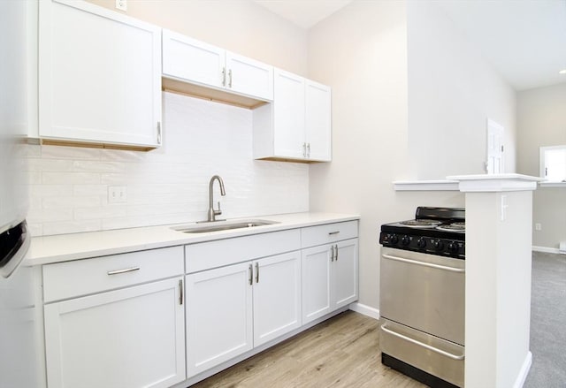 kitchen featuring sink, white cabinetry, stainless steel range, kitchen peninsula, and light hardwood / wood-style floors