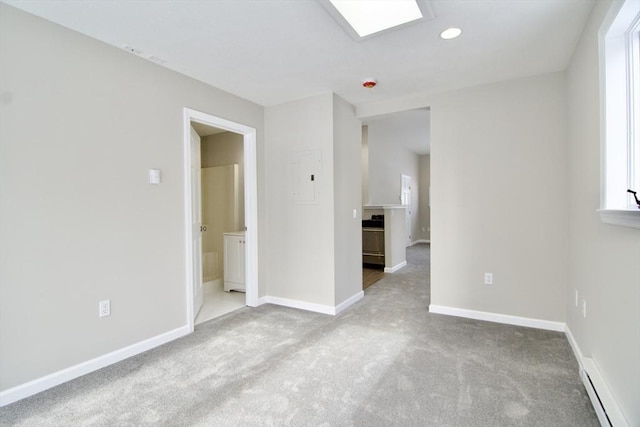 carpeted empty room with baseboard heating and a skylight