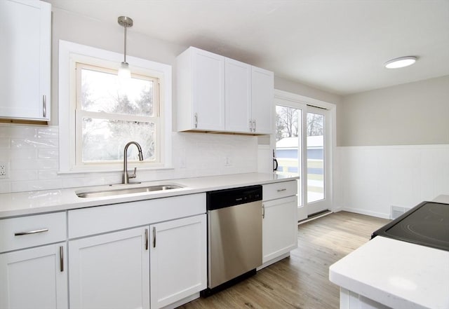 kitchen with pendant lighting, sink, light hardwood / wood-style flooring, white cabinetry, and stainless steel dishwasher