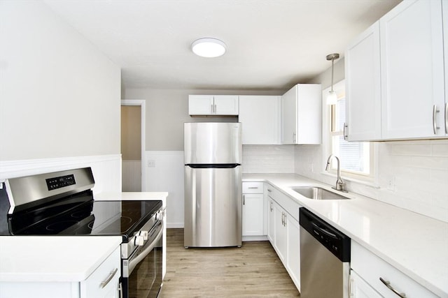 kitchen with sink, decorative light fixtures, stainless steel appliances, light hardwood / wood-style floors, and white cabinets