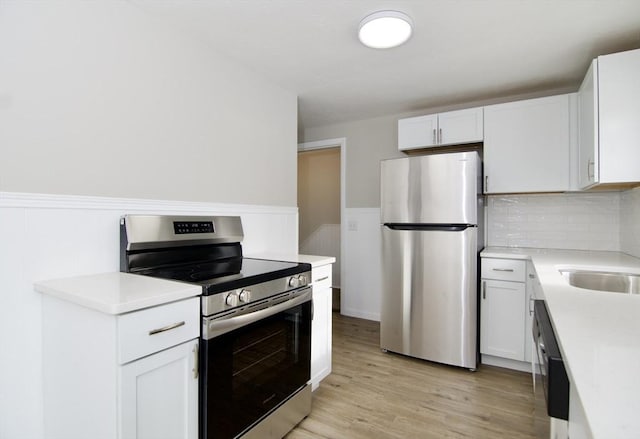 kitchen featuring white cabinetry, appliances with stainless steel finishes, light hardwood / wood-style flooring, and backsplash