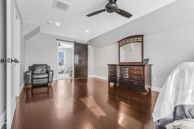 interior space with lofted ceiling, dark hardwood / wood-style floors, ceiling fan, and a barn door