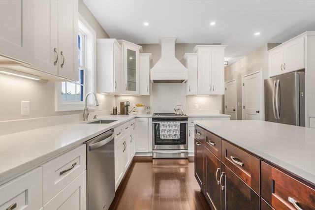 kitchen with sink, premium range hood, white cabinets, dark wood-type flooring, and stainless steel appliances