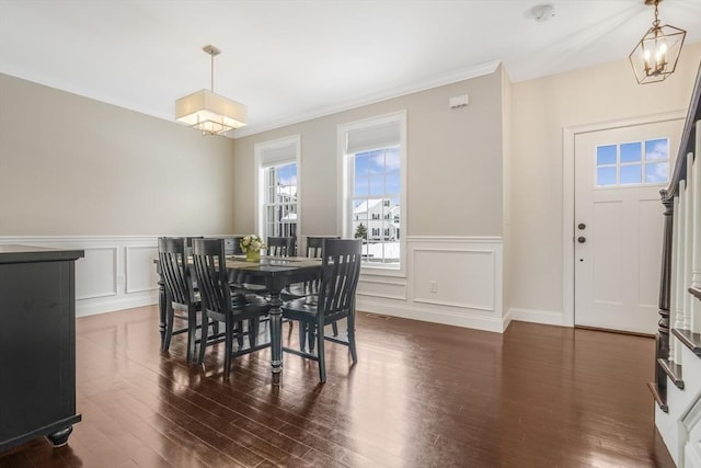 dining room featuring dark wood-type flooring, a notable chandelier, and ornamental molding