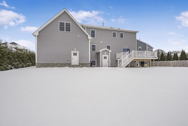 snow covered house with a wooden deck