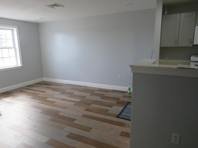 interior space featuring visible vents, light wood-style flooring, and baseboards