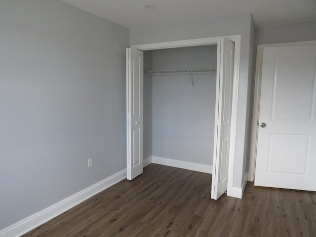 unfurnished bedroom with a closet, baseboards, and dark wood finished floors