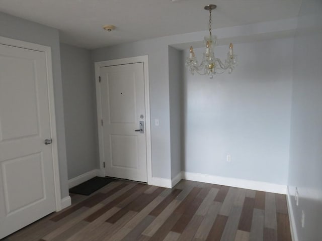 interior space featuring a notable chandelier, wood finished floors, and baseboards