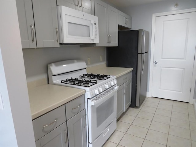 kitchen featuring white appliances, light tile patterned floors, light countertops, and gray cabinetry