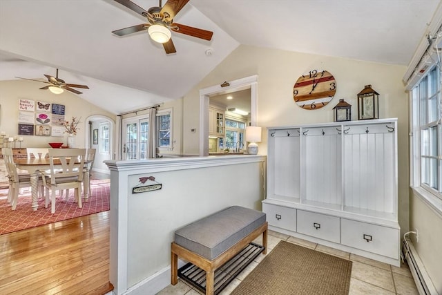 interior space with ceiling fan, light tile patterned floors, a baseboard radiator, and lofted ceiling