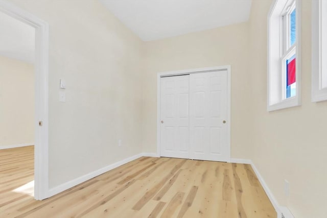 unfurnished bedroom featuring a closet, baseboards, and wood finished floors