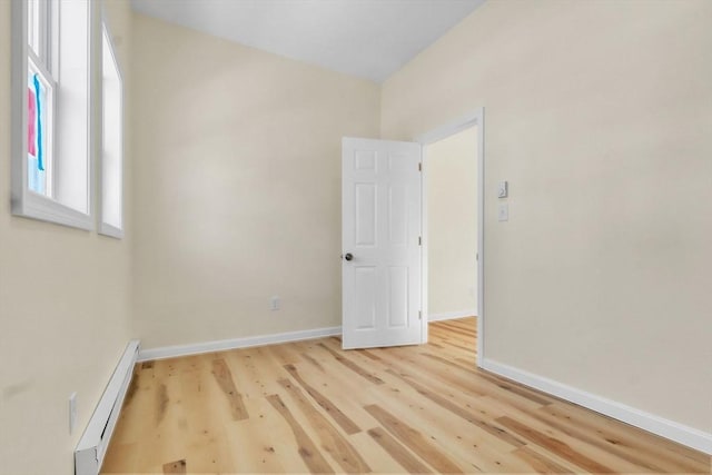 spare room featuring baseboards, baseboard heating, and wood finished floors