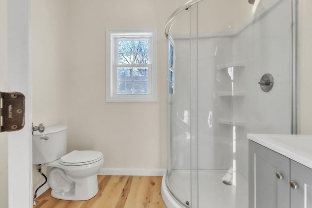 bathroom featuring vanity, wood finished floors, baseboards, a stall shower, and toilet