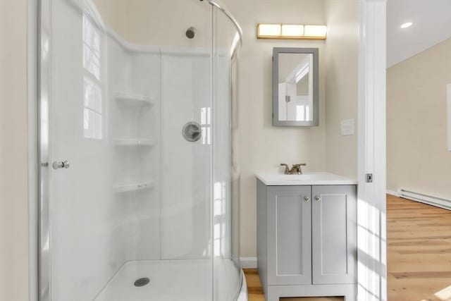 full bath with a baseboard heating unit, a shower stall, wood finished floors, and vanity