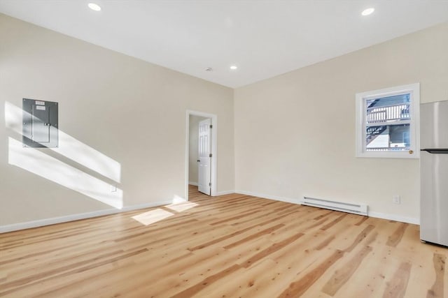 spare room featuring electric panel, a baseboard heating unit, wood finished floors, and recessed lighting