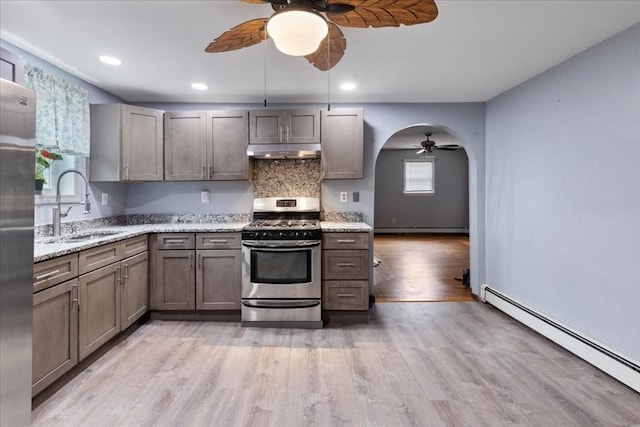 kitchen featuring baseboard heating, appliances with stainless steel finishes, sink, and light stone counters