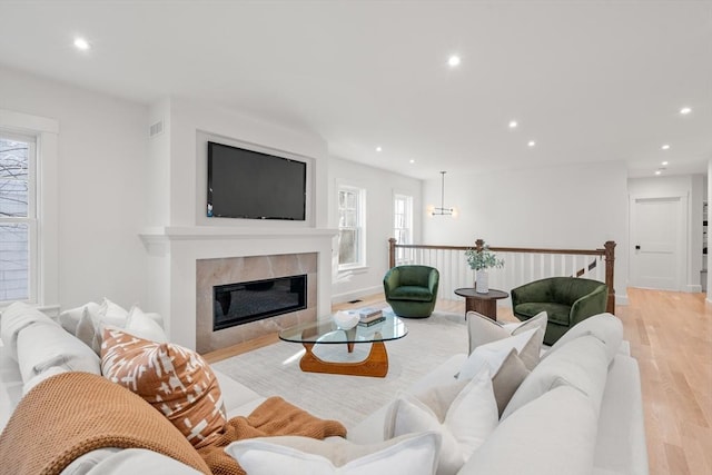 living room featuring a tiled fireplace and light hardwood / wood-style floors