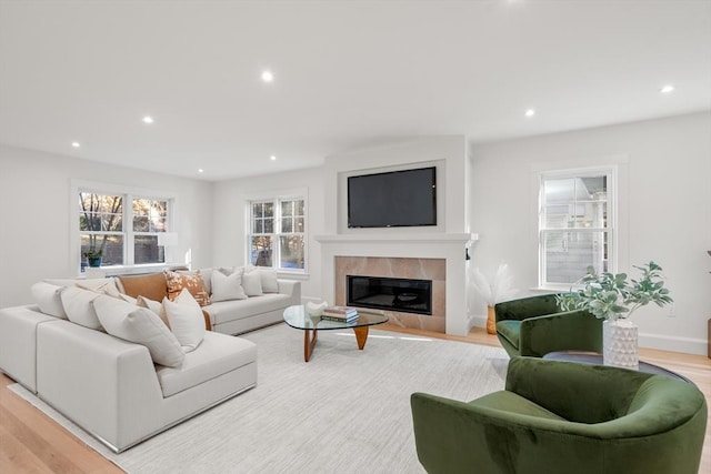 living room with a tile fireplace and light hardwood / wood-style flooring