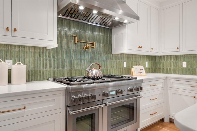 kitchen with range with two ovens, white cabinetry, and extractor fan