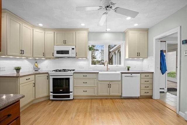 kitchen featuring a sink, cream cabinets, white appliances, and light wood-style flooring