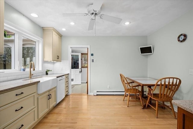 kitchen featuring white dishwasher, light stone counters, a sink, light wood-style floors, and recessed lighting