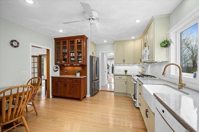 kitchen with decorative backsplash, white appliances, light stone countertops, recessed lighting, and light wood finished floors