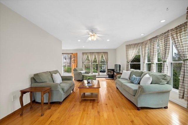 living room with light wood-type flooring, a ceiling fan, baseboards, and recessed lighting