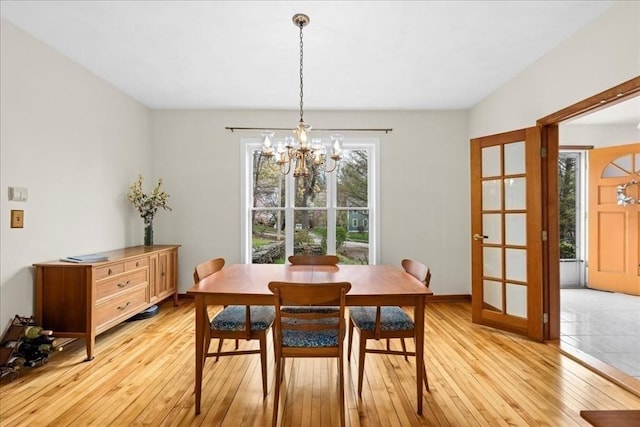 dining room with baseboards, light wood-style flooring, and a chandelier